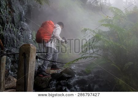 A Man Is Crossing The Path Of A Hot Spring Stream In The Gunung Gede Pangrango Forest
