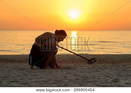 Man With Metal Detector On The Beach In Sun Set Time
