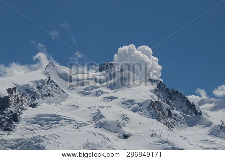 Snowy And Icy Summit Of Dufourspitze Mountain With Cumulus Cloud, Blue Sky