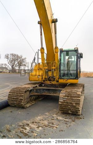Excavator With Dirty Grouser Pad Parked On A Road