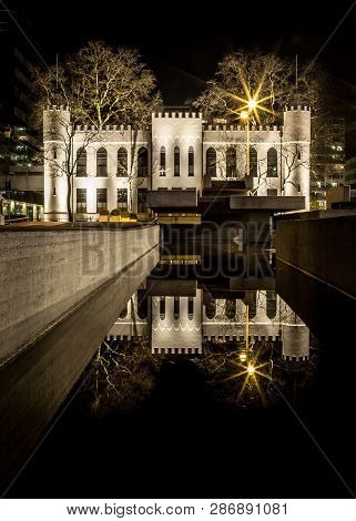 Mystic City Hall Of Tilburg At Night With Reflection In The Water On Netherlands. Historic Dutch Arc