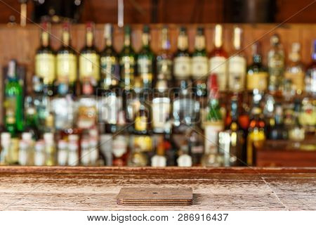 Coaster Under Glass On Blurred Bar Background. Empty The Top Of Wooden Table With Blurred Counter Ba