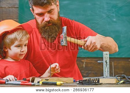 Workshop And Handyman Concept. Boy, Child Busy In Protective Helmet Learning To Hammering Hobnails W