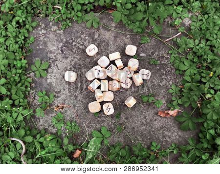 A Stack Of Wooden Runes At Forest. Wooden Runes Lie On A Rock Background In The Green Grass. Runes A