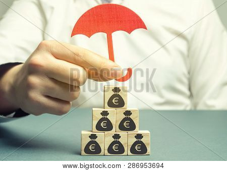Insurance Agent Protects Wooden Blocks With The Image Of The Euro. Savings Protection. Keeping Money