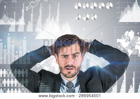 Confused Young Businessman With Beard Wearing Dark Suit And Looking Forward Standing Over Gray Backg