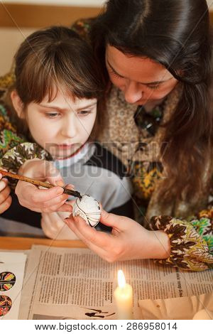Lviv, Ukraine - March 11, 2018. Mom And Daughter Paint Easter Eggs At The Table