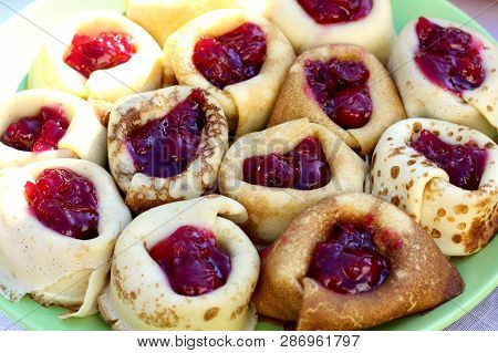 Thin Ruddy Pancakes On Milk With Cherry Jam, Wrapped Rolls. Pancakes Are Packed Tightly On A Large D