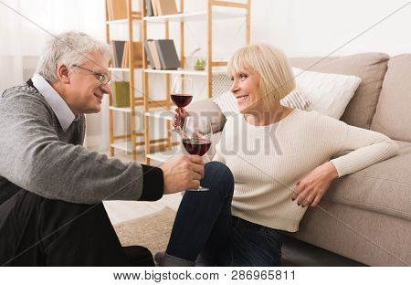 Loving Senior Couple Enjoying Wine, Having Rest At Home