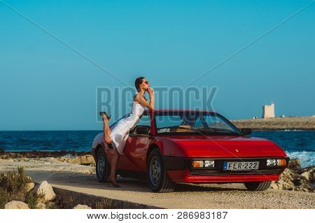 Young Beautiful Girl In Sunglasses Posing Near The Red Ferrari