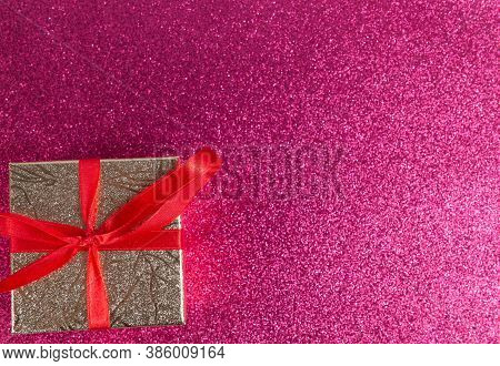 Gift With A Red Ribbon On A Shiny Pink Background With Copy Space