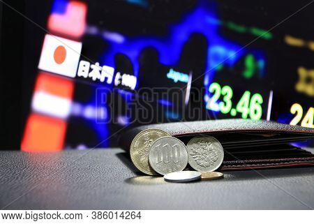 Pile Of Japanese Yen Coins (jpy) On Black Floor With Black Wallet And Digital Board Of Currency Exch