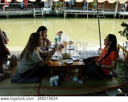Amphawa, Thailand, January 23, 2016: Three Women Enjoy Food On The Edge Of The Canal At Amphawa Floa
