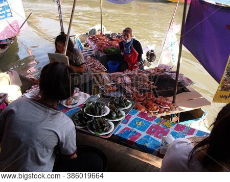 Amphawa, Thailand, January 23, 2016: A Waitress Receives Trays Of Food From A Boat At Amphawa Floati