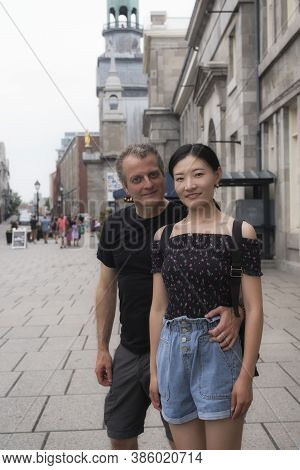 A Causasian Man And Chinese Woman Couple Standing On A Sidewalk In Old Montreal In Quebec Canada On 