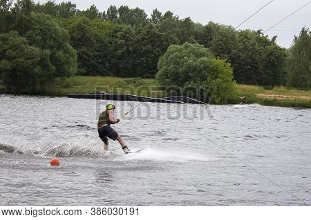 A Wakeboarder On A Wakeboard Landed In The Water, Surrounded By Splashes. Two Men Wakeboarding On Th