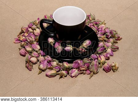 A Black Mug With A Saucer With Tea Made From Dried Buds And Petals Of A Purple Damask Rose Stands On