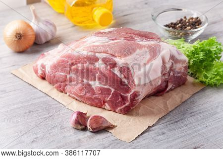 A Piece Of Uncooked Meat Of Pork Neck On Black Stome Plate With Ingredient On Gray Table. Ready To B