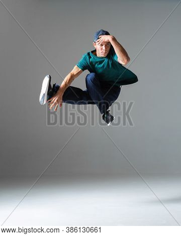 Cool Young Guy Breakdancer Jumps In Studio Isolated On Gray Background. Dance School Poster. Break D