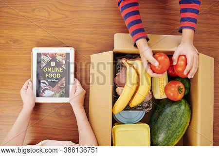 Woman Opening Food Delivery Application On Tablet Computer To Check The Order When He Son Taking Tom