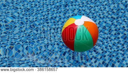 Beach Ball In Pool. Colorful Inflatable Ball Floating In Swimming Pool, Summer Vacation Concept.