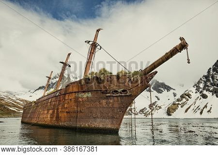 An Abandoned Ship In Antarctica, Abandoned Ship At The North Pole With Ice Mountains In The Backgrou