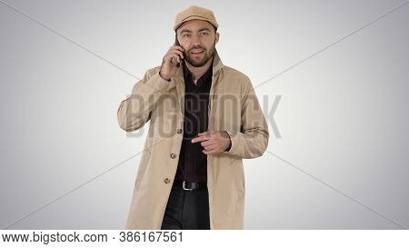 Young Fashionable Businessman Talking On Mobile Phone On Gradien