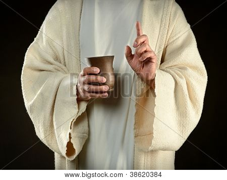 Mani di Gesù tenendo la tazza di vino isolato su sfondo scuro