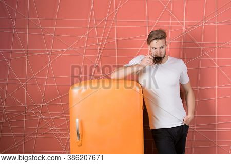 Bachelor With Morning Drink At Refrigerator. Man Hold Cup Of Tea Or Coffee In Kitchen. Macho Drink A