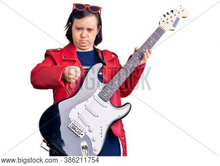 Brunette woman with down syndrome playing electric guitar annoyed and frustrated shouting with anger, yelling crazy with anger and hand raised 