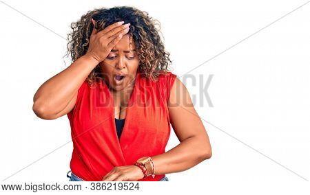 Young african american plus size woman wearing casual style with sleeveless shirt looking at the watch time worried, afraid of getting late 