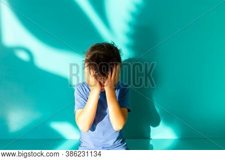 Portrait Of A Sad Or Frustrated Brunette Boy In A Blue Shirt. Thumbs Up. Turquoise Background With S