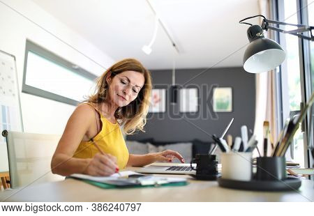 Mature Woman Working Indoors In Home Office In Container House In Backyard.