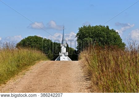 The Steeple Of An Old Country Church Rises Above The Hill And Path Of Prairie Grass