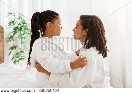 Mother Daughter Relationship. Cute Little Black Girl And Her Mom In Bathrobes Embracing At Home, Bon