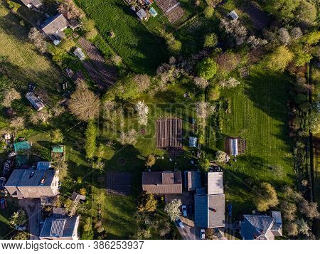 Areal Suburbs View With House Roofs, Gardens In A Evening Sun Light. Photo Taken In Latvia