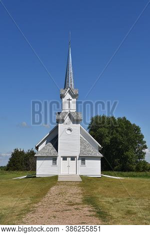 An Old Country Church Rises Above The Hill And Path Of Prairie Grass