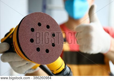 Close-up Of Sander In Hands Of Builder Showing Ok Or Good Gesture. Handyman With Sandpaper Appliance