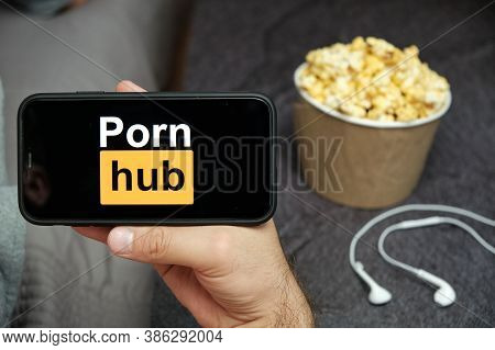 Close Up Mans Hand Holding A Mobile Phone With Porn Hub Logo With Apple Earphones And Popcorn Box Ne