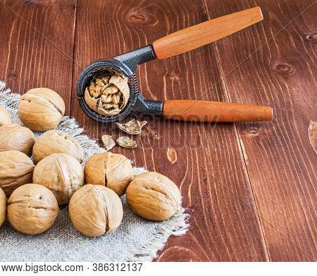 Close-up Of A Walnut And Nutcracker. Freshly Cracked Walnut In A Nutcracker On A Wooden Background A