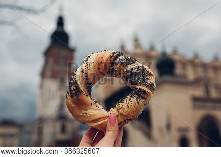 Tourists Holding Bagel Obwarzanek Traditional Polish Cuisine Snack On Market Square In Krakow. Trave