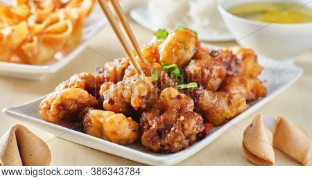 using chopsticks to eat chinese general tsos chicken meal with crab rangoon and egg drop soup