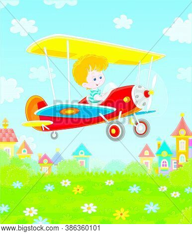 Little Cheerful Boy Piloting His Small Toy Plane Among White Clouds In Blue Summer Sky Over A Green 