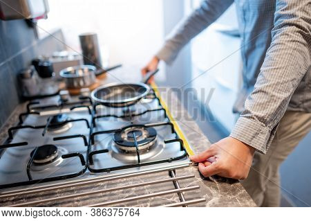 Male Hand Interior Designer Using Tape Measure On Gas Stove On Modern Countertop In Kitchen Showroom