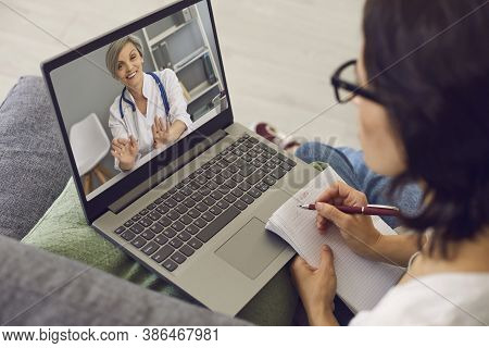 Woman Patient Making Notes During Online Consultation With Woman Doctor Consulting Her From Laptop