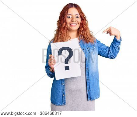 Young latin woman holding question mark pointing finger to one self smiling happy and proud 