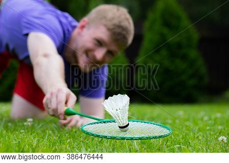 Close Up Badminton Player With Racket In Action. Young Man On Grass Playing Badminton Outdoors. Spor