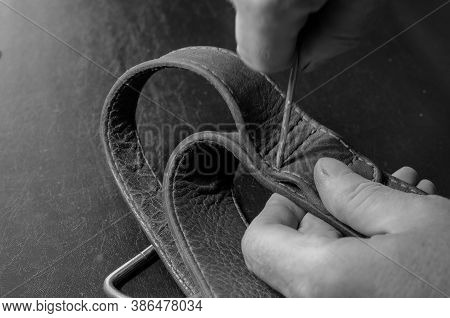 A Man Makes Holes In A Leather Collar With An Awl. Hands Of An Adult Man With A Metal Awl And A Wide
