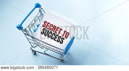 Shopping Cart And Text Secret To Success On White Paper Note List. Shopping List Concept On Blue Bac