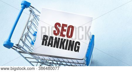 Shopping Cart And Text Seo Ranking On White Paper Note List. Shopping List Concept On Blue Backgroun